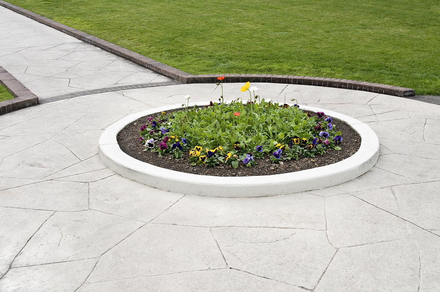 Stamped concrete sidewalk with circular flower garden in the middle