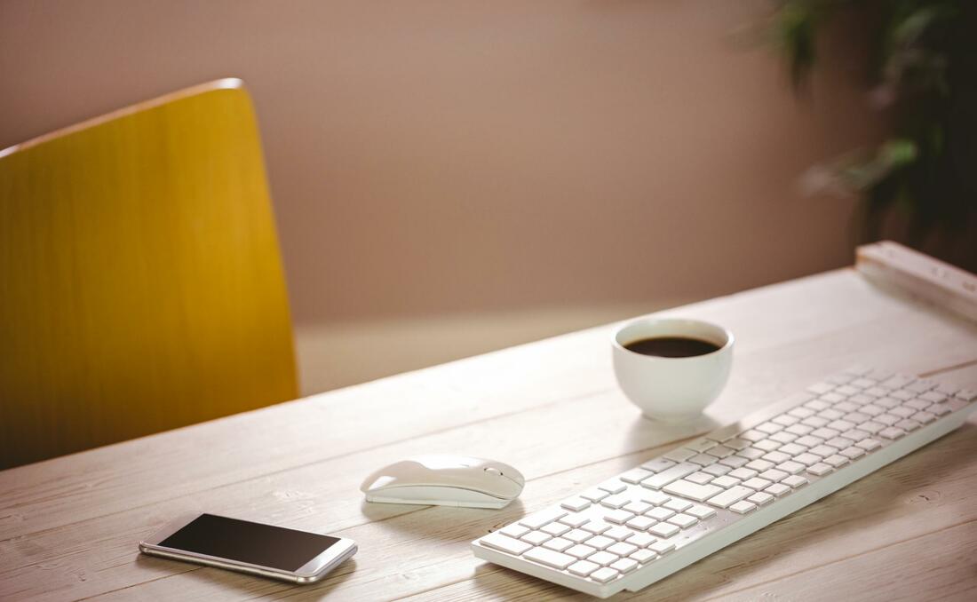 Keyboard on desk with coffee and phone. Contact us online.